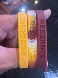 The Washington Redskins Adult Mylar NFL Team Logo + Color 3pk Wristbands Bracelet is a set of three wristbands featuring the iconic team logo and colors of the Washington Commanders.